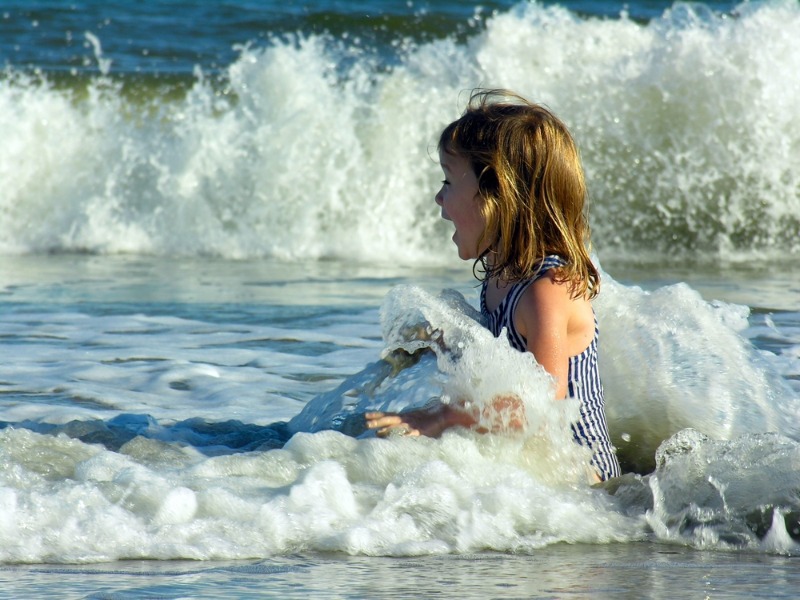 Charleston Kids Activities: A youngster laughs joyfully as the tide rolls in on Folly Beach near Charleston, SC.