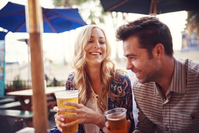 Folly Beach Restaurants: A young couple smiles while taking sips of draught beer at a Folly Beach restaurant.
