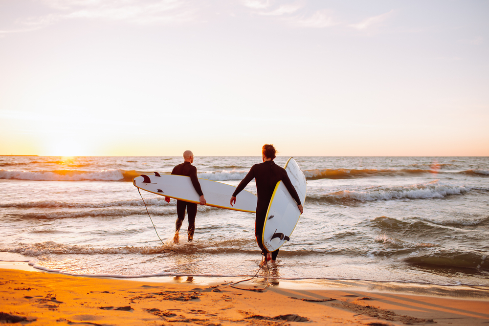 Two people walking towards water with surfboards in Folly Beach